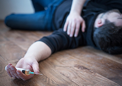 Man lying down on the floor requiring naloxone after a drug overdose
