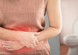 Woman with travelers' diarrhea holding her stomach appearing to be in pain