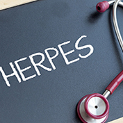 Genital herpes treatment, suggested by the word 'herpes' written on a chalkboard with a stethoscope lying on it