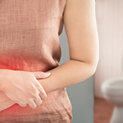 Woman with traveler's diarrhea holding her stomach appearing to be in pain
