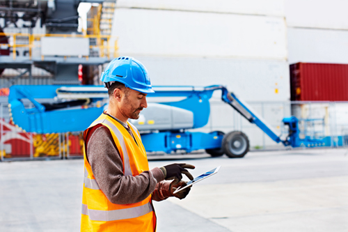 Shot of a young man in workwear using a digital tablet while standing on a large commercial dock