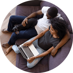 Couple sitting on couch accessing online medical treatment